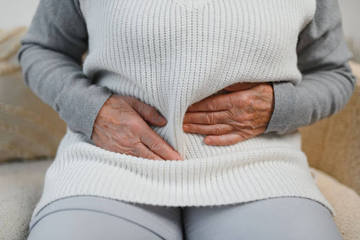 Senior woman holding her stomach, illustrating common menopause symptoms such as digestive discomfort, which can be influenced by changes in gut health.